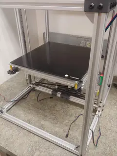 Thumbnail: The glass build platform rests on an aluminum plate with a 750W silicone heater pad on the bottom. This plate mounts to the sub-frame with stiff yellow springs in each corner, so the bed can be coarsely leveled