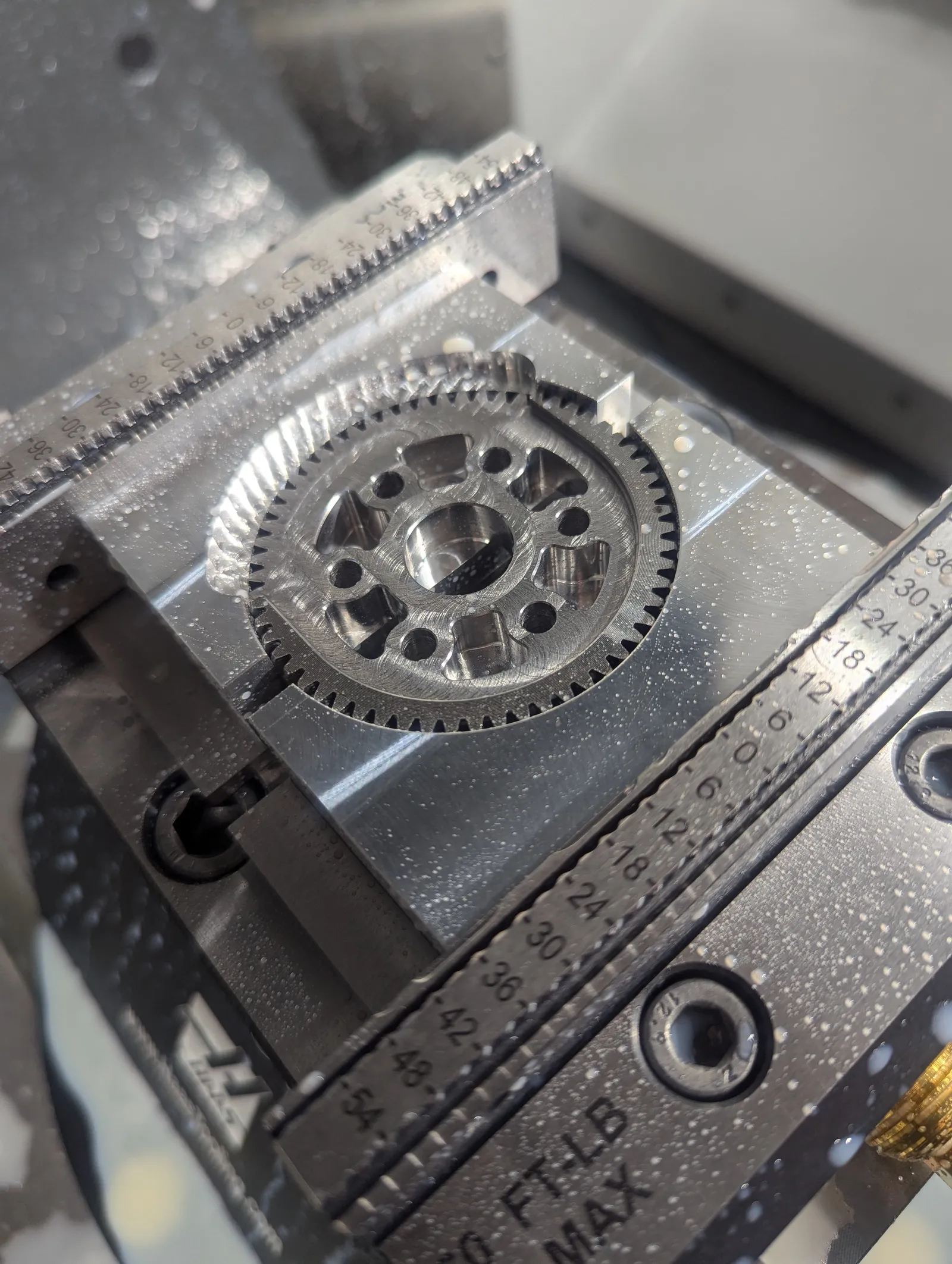 A lifter output gear just after machining, held in a pair of aluminum soft jaws in a mill vice