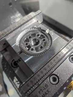 Thumbnail: A lifter output gear just after machining, held in a pair of aluminum soft jaws in a mill vice